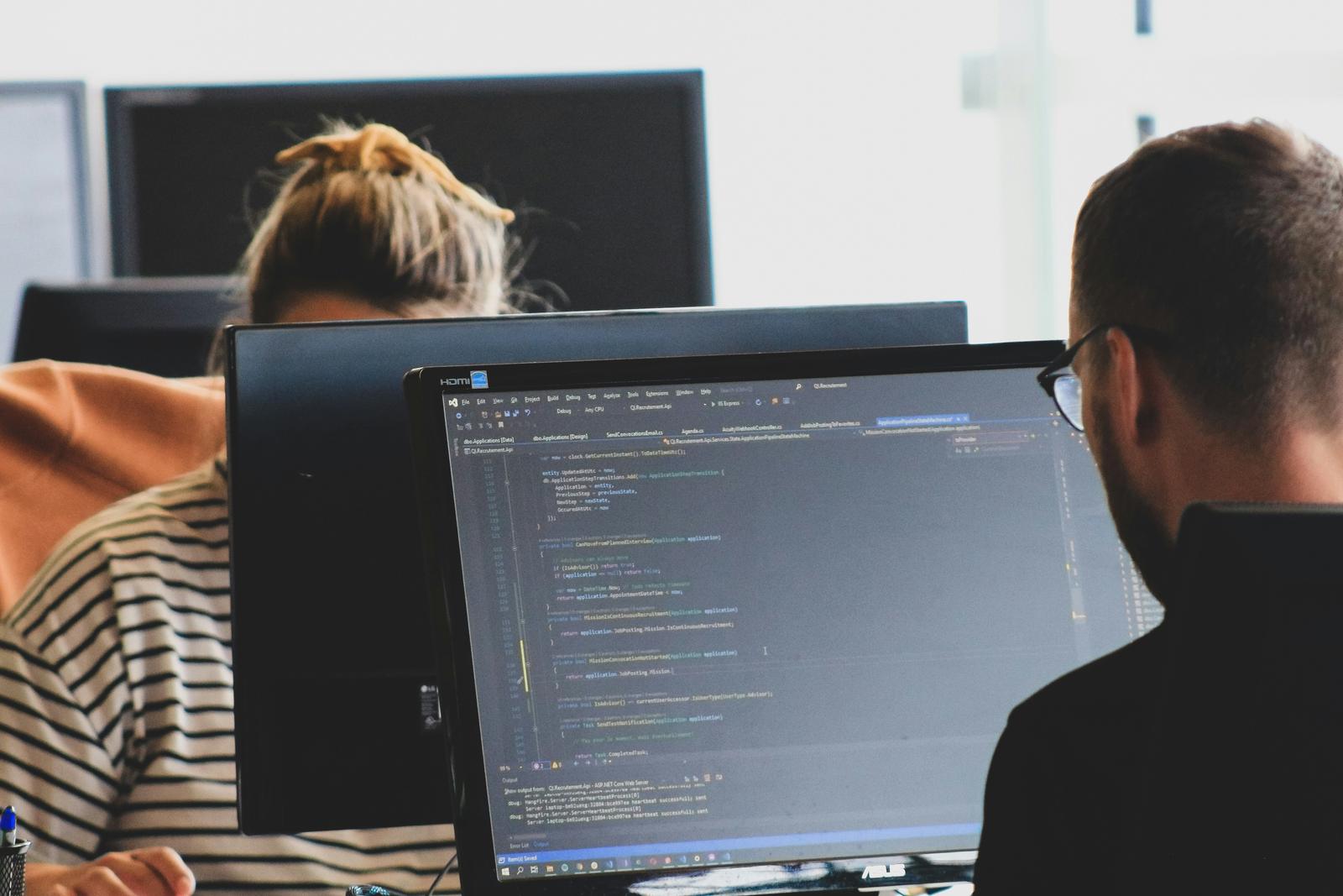 Two developers working on code at their monitors