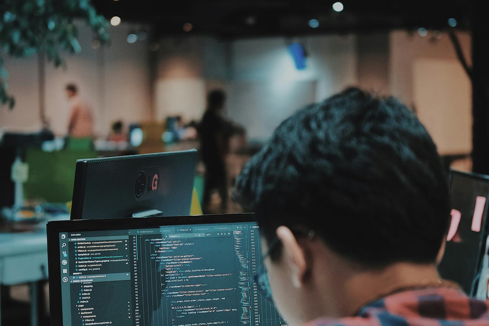 Software developer writing code at a multi-monitor workstation